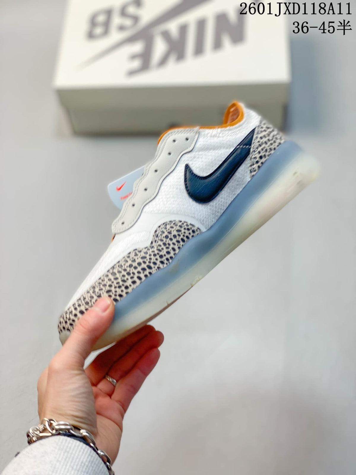 Side view of the Nike SB PS8 sneaker showing the dark Nike Swoosh, white upper, patterned overlays and translucent sole.