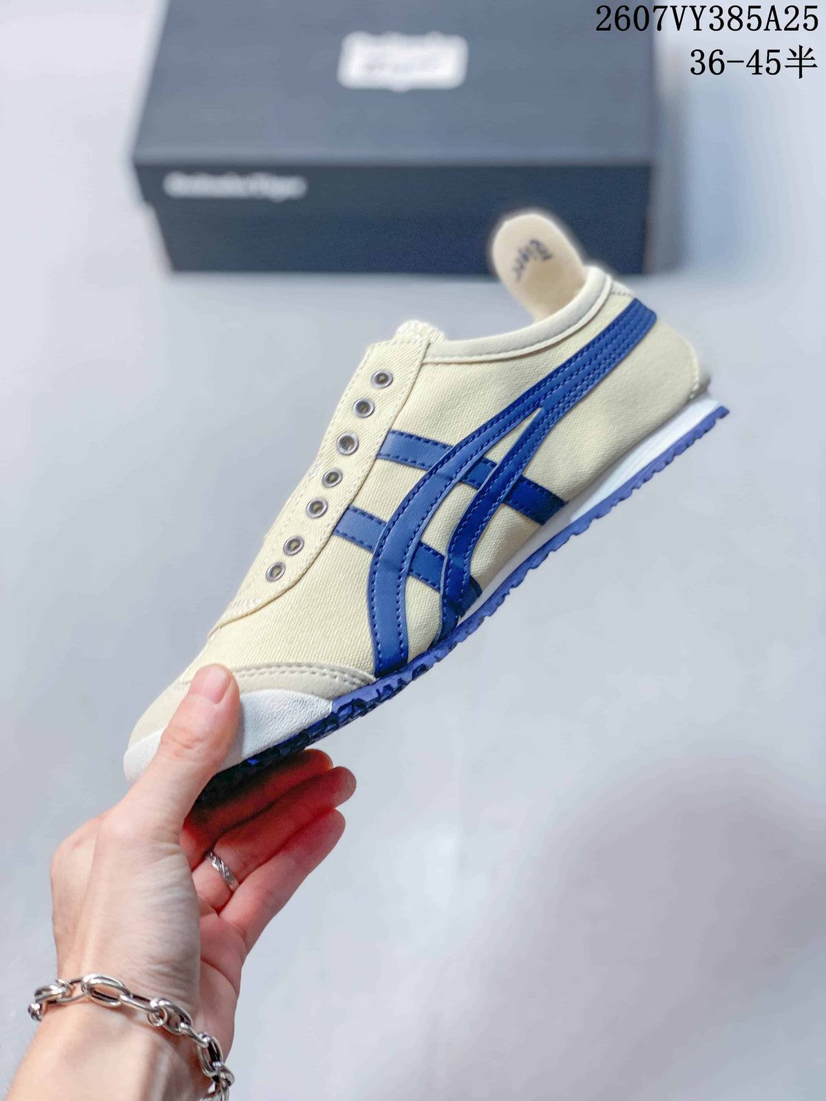 Side view of the cream and blue sneaker showing the stripe pattern, decorative eyelets, white midsole, and blue outsole.