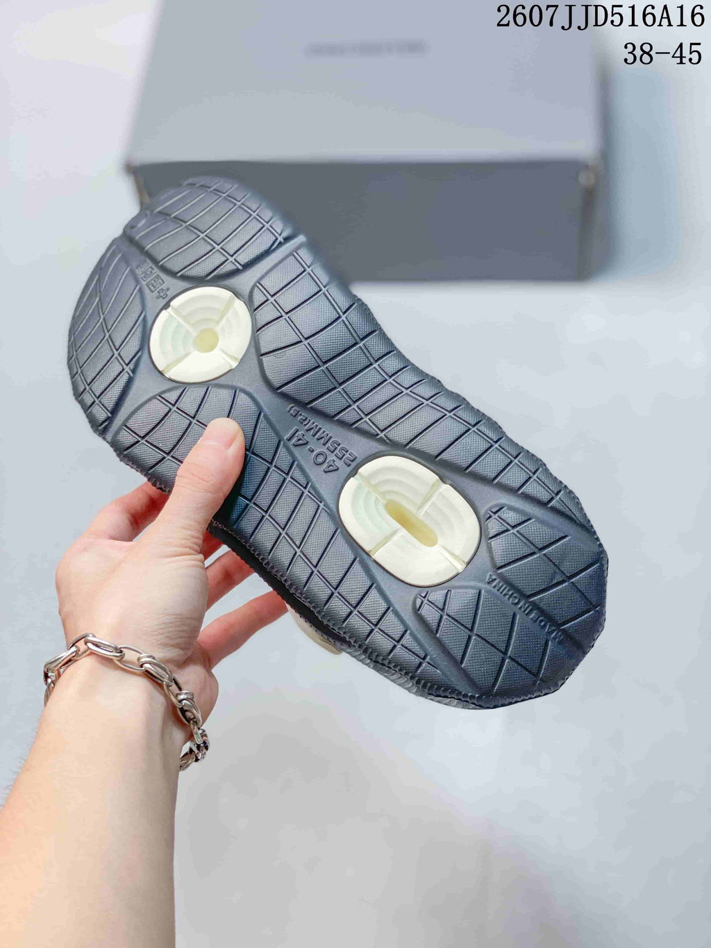 Underside view of the sandal showing the patterned outsole and two white circular sole details.