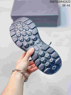 Close view of the dark gray sneaker outsole showing its geometric lug pattern and textured traction areas.