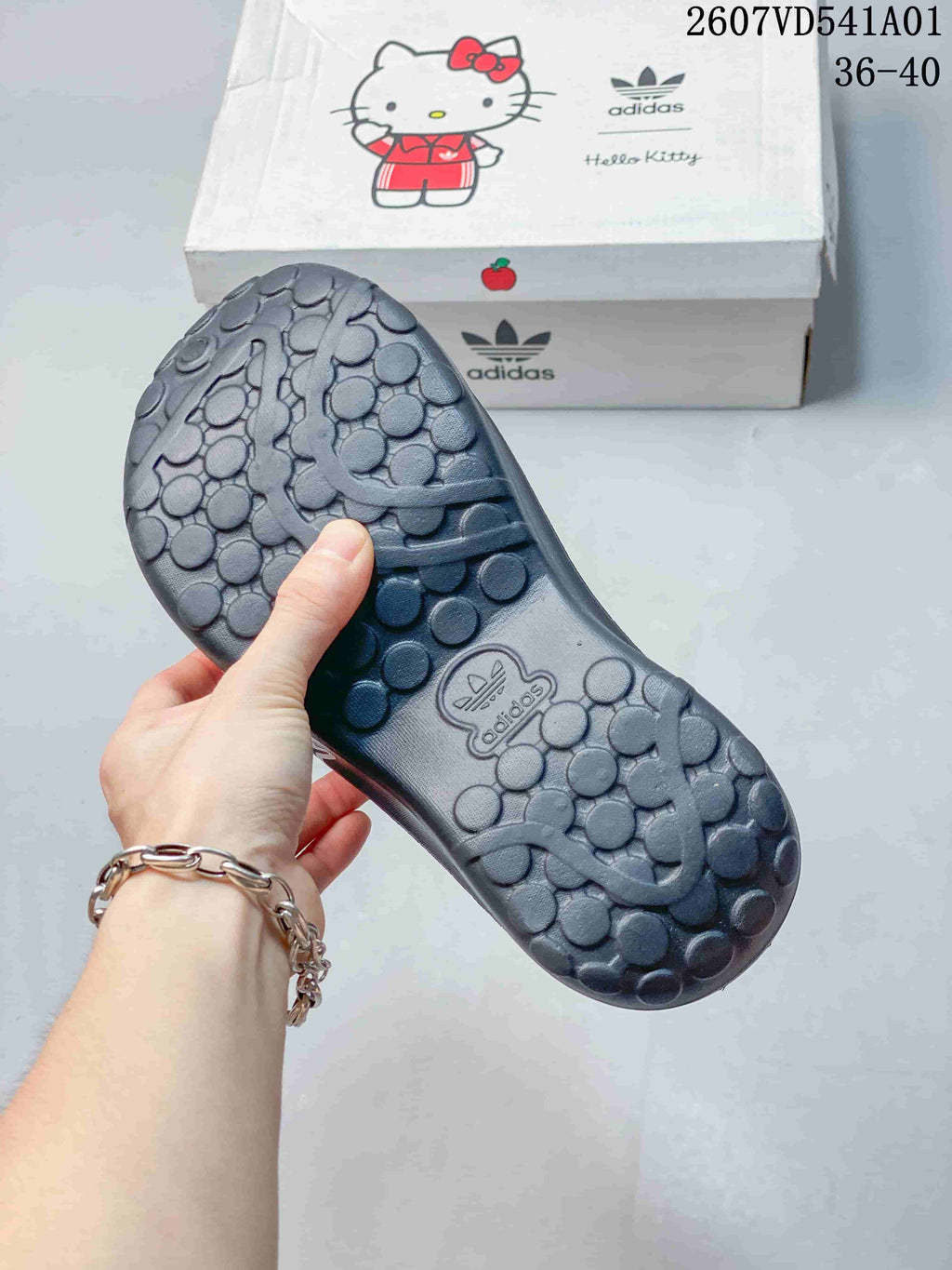 Textured outsole of a charcoal clog mule, with a Hello Kitty and adidas-branded box in the background.