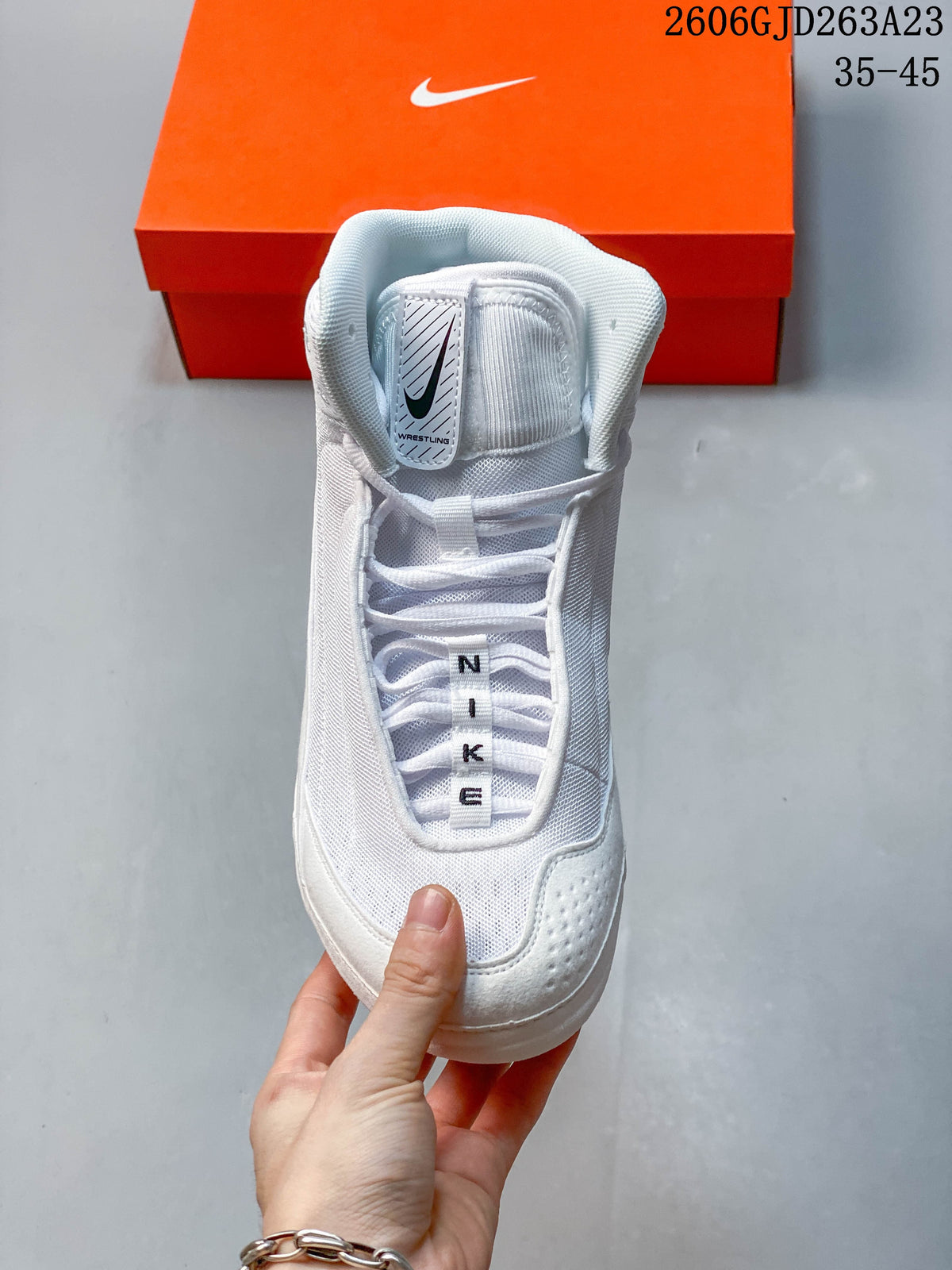 Front view of a white Nike Inflict 4 wrestling shoe showing its laces and tongue label.