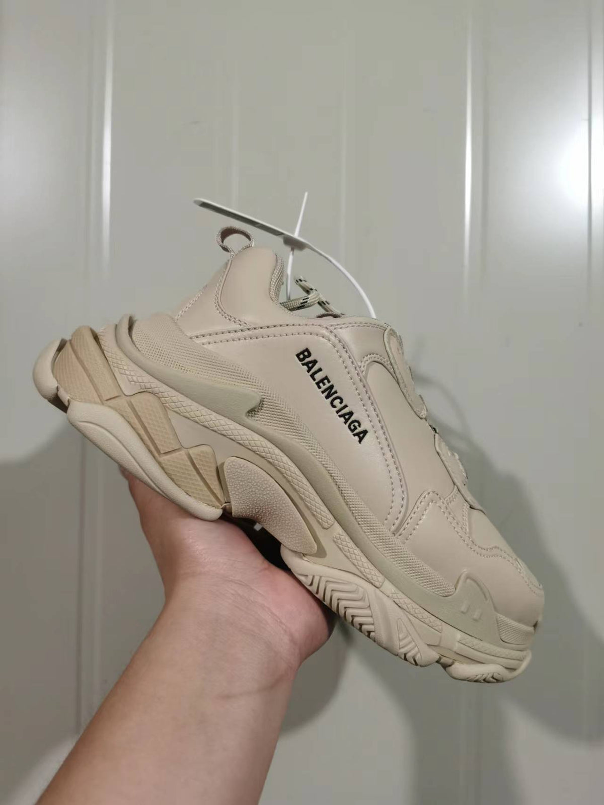 Side view of the beige Balenciaga Triple S sneaker showing layered panels, textured sections, and the sculpted outsole.