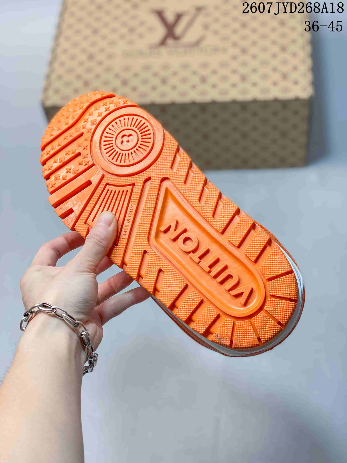Close view of the orange outsole showing raised branding and a patterned tread.
