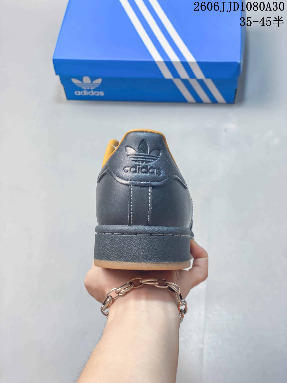 Rear view of a charcoal adidas Superstar sneaker showing the heel tab and sole