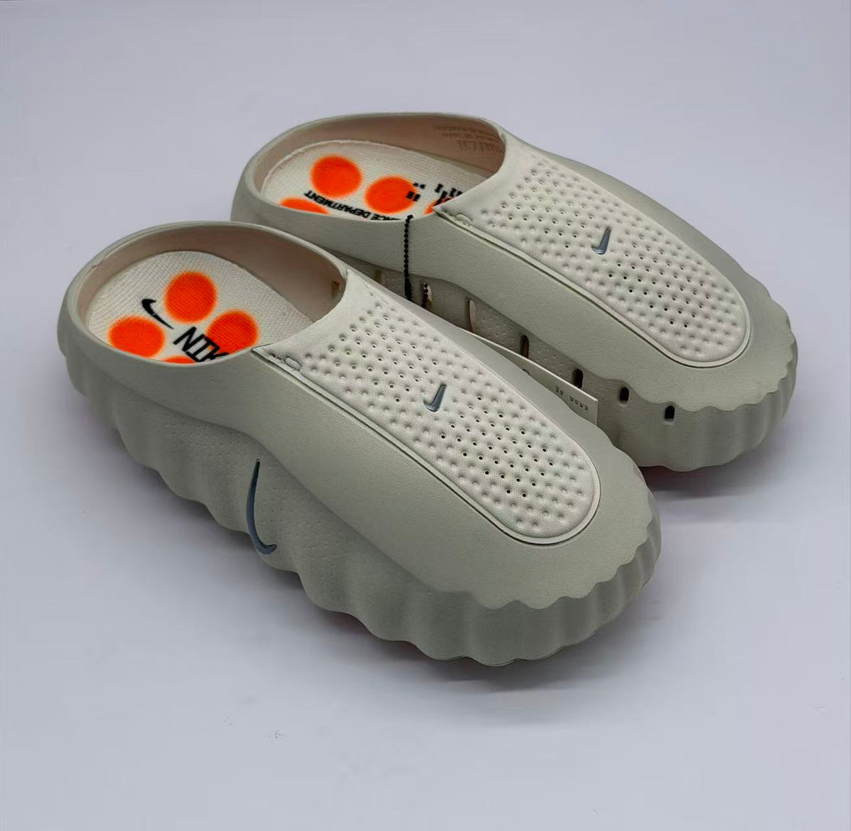 Top three-quarter view of the pair, showing perforated footbeds, dark Swoosh details, and orange insole graphics.