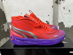 Side view of a red Puma Melo basketball shoe with a metallic-look stripe and purple graphic sole.