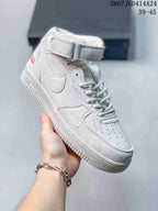Angled side view of a white and light-gray mid-top sneaker showing the Swoosh detail, perforated toe, ankle strap, and raised sole.