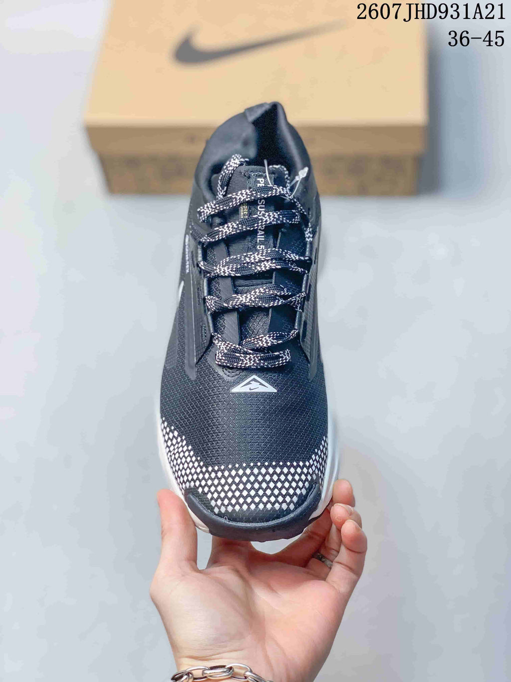 Top view showing the patterned laces, dark upper, triangular tongue logo, and reflective checkerboard toe panel.