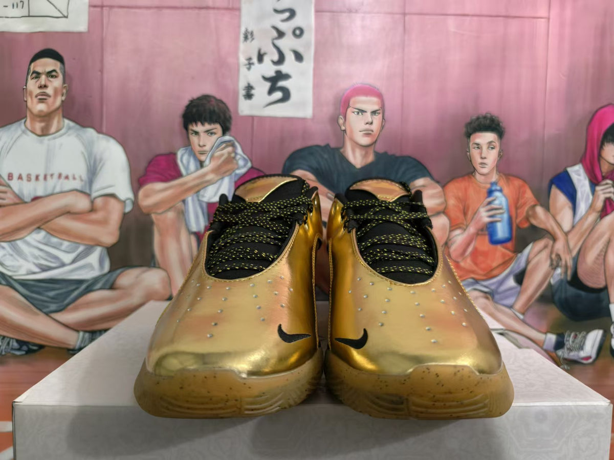 Front view of gold-tone Nike sneakers showing black patterned laces and translucent gum-colored outsoles.