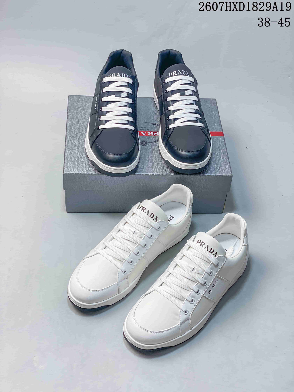 Navy and white Prada Downtown low-top sneakers displayed together, showing branded tongues, lace-up fronts and contrasting soles; style code 2607HXD1829A19 and size range 38–45 are visible.