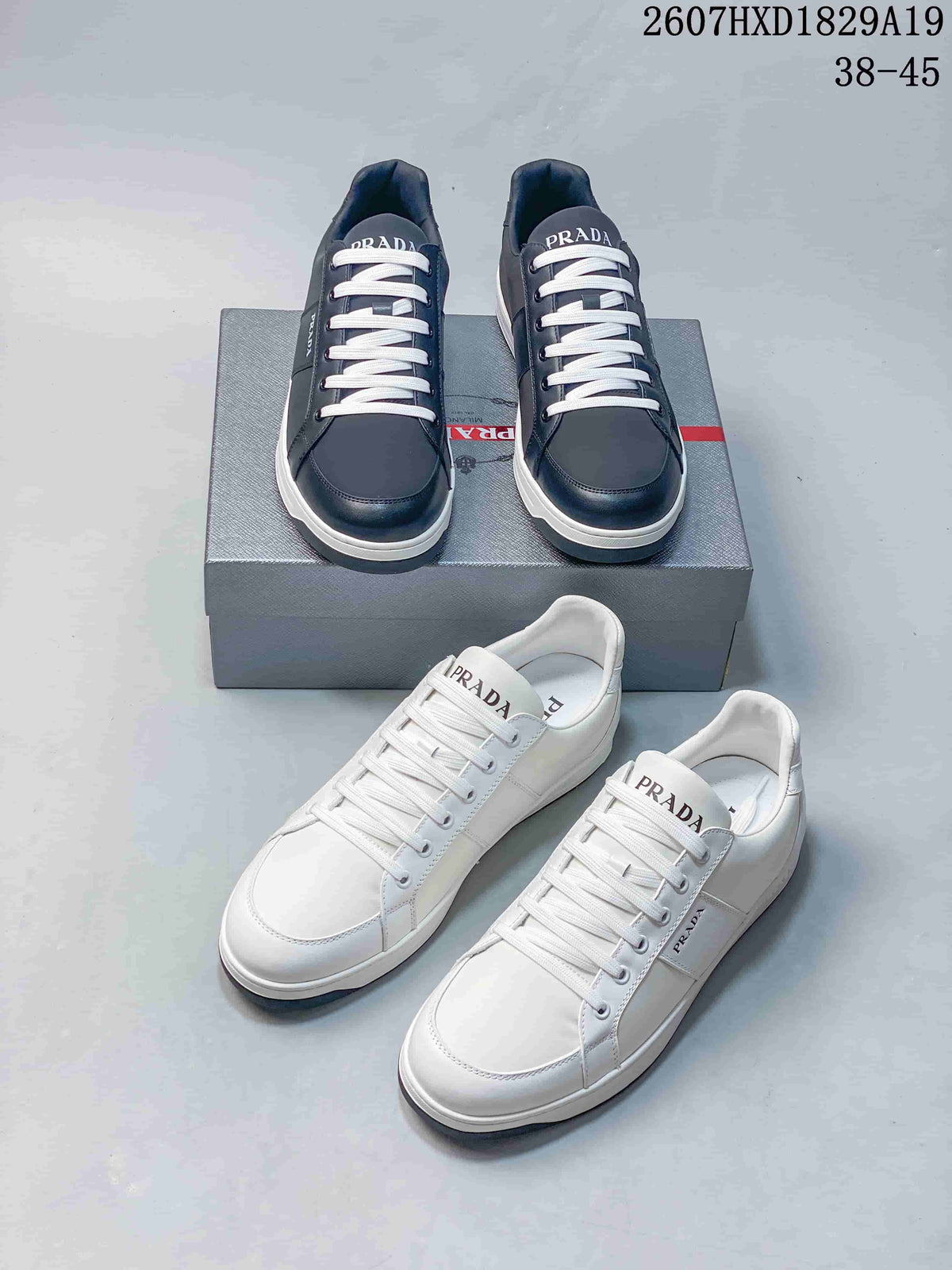 Navy and white Prada Downtown low-top sneakers displayed together, showing branded tongues, lace-up fronts and contrasting soles; style code 2607HXD1829A19 and size range 38–45 are visible.