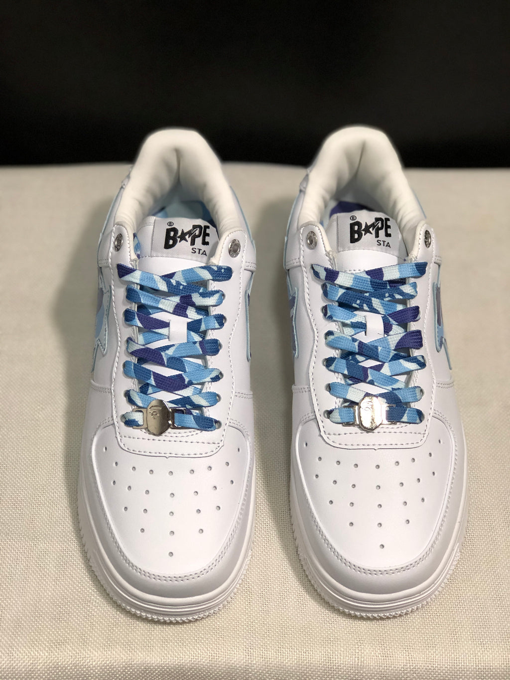 Front top view of the pair showing the perforated white toe panels and blue patterned laces with metal accessories.
