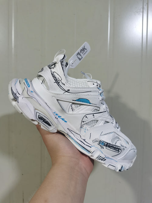 Close angled view of the white sneaker showing mesh sections, black graphic lines, blue accents, and lace-up construction.