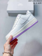 Side view of the white low-top sneaker with a white Swoosh and purple outsole edge.