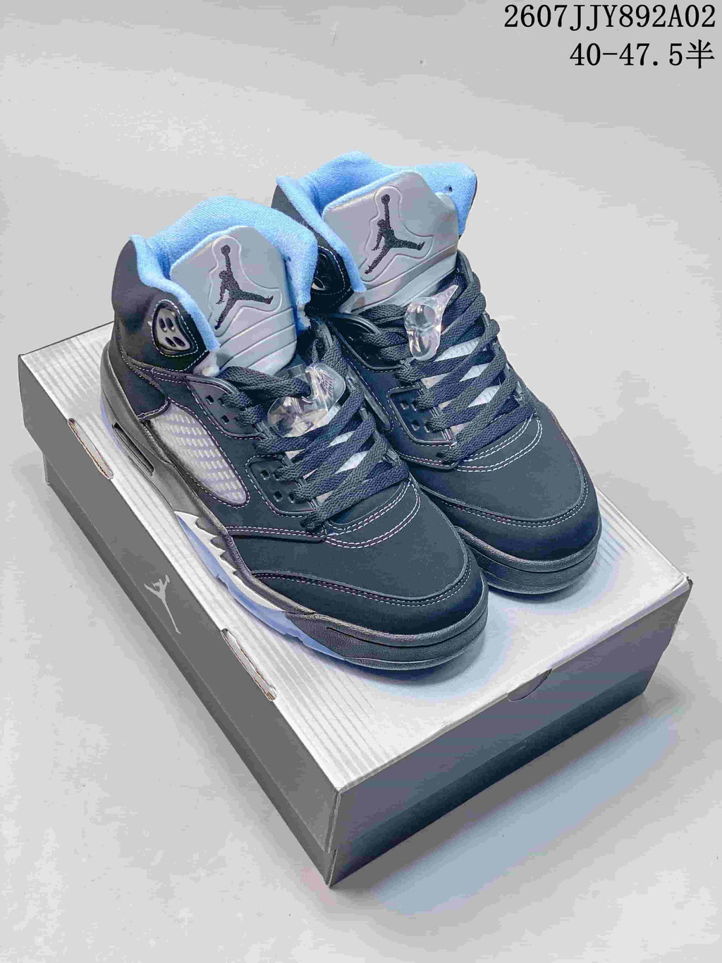 Pair of dark Air Jordan 5 Low sneakers with light blue accents on a shoebox