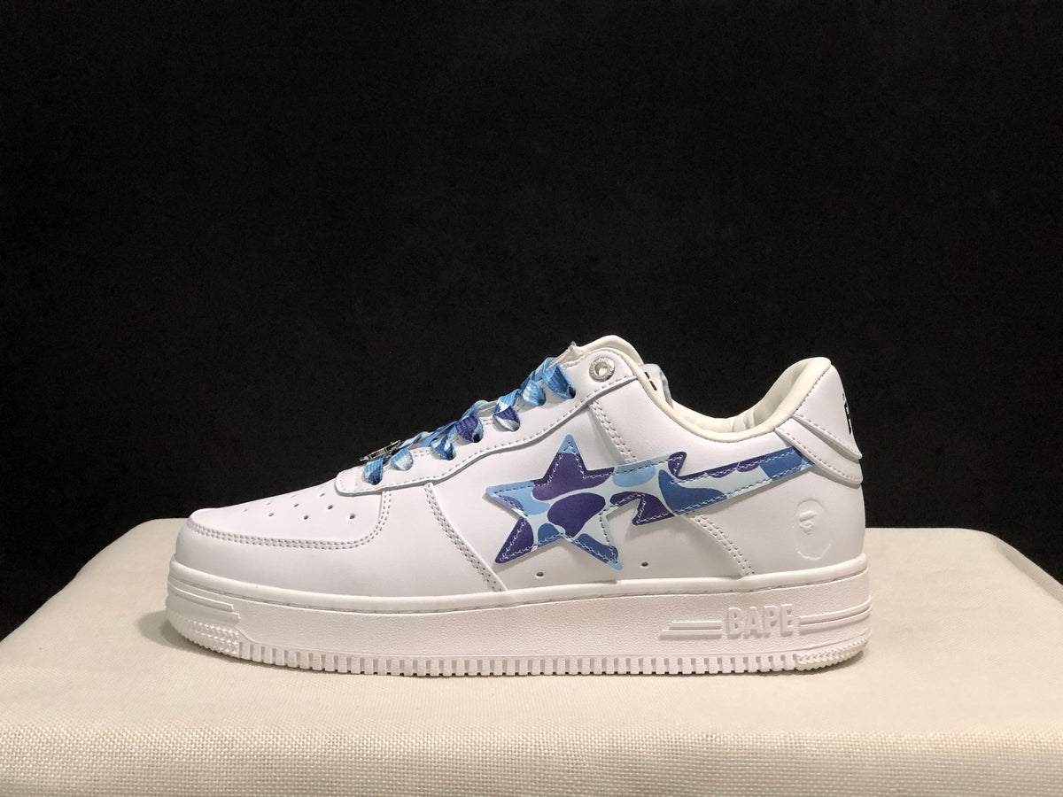 Side profile of a white BAPE STA sneaker showing the blue camouflage star-shaped side detail and white rubber sole.