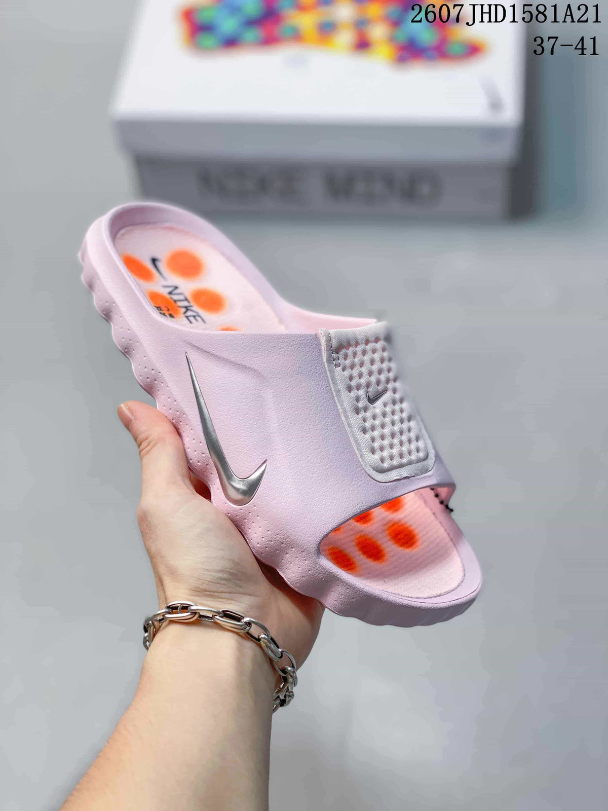 Angled view of the light pink Nike mule slide showing the side Swoosh, wide upper and orange outsole pods.