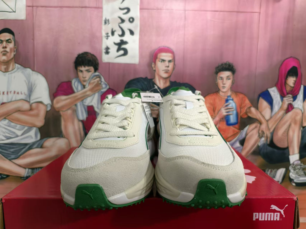 Front view of off-white PUMA sneakers with green accents, laces, and textured toe panels.