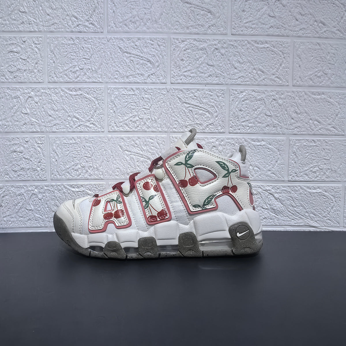 Side profile of a white cherry-print Nike Air More Uptempo sneaker