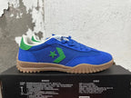 Side view of a blue Converse shoe with green star-and-chevron detailing and a gum-colored outsole
