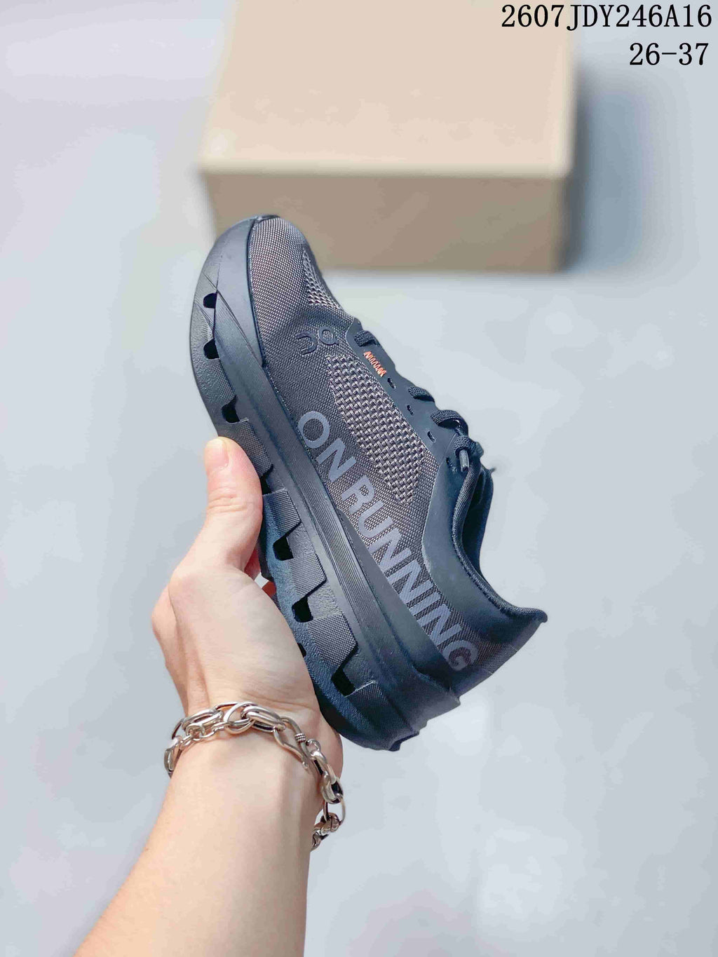 Side view of the dark gray sneaker showing the large On branding, textured upper, and chunky sole.