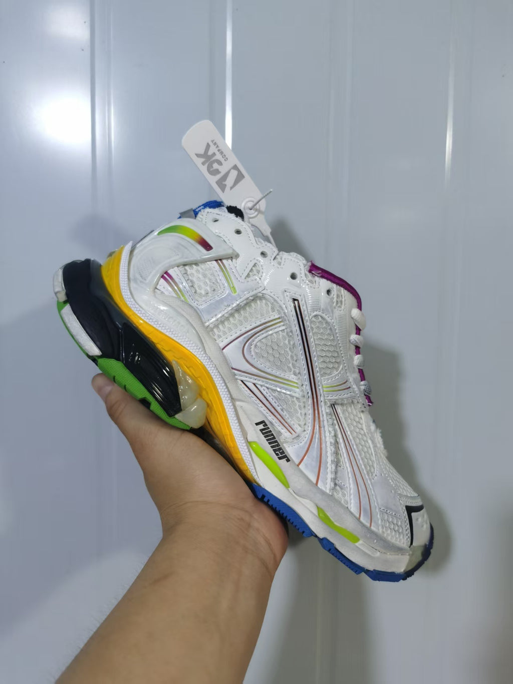 Angled close-up of a white Puma Runner Gradient sneaker showing multicolor overlays, mesh panels and a colorful outsole.
