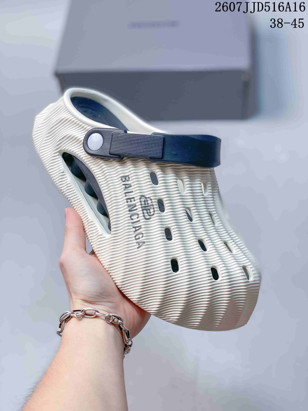 Side view of a white and navy perforated clog showing the rear strap, textured upper, and visible logo.