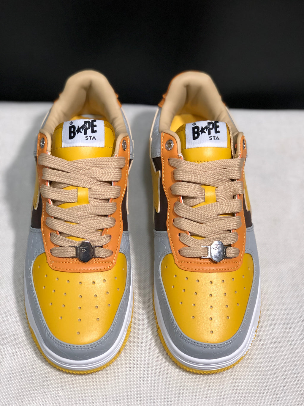 Front top view showing the yellow toe boxes, beige laces, tongue labels, and padded collars.