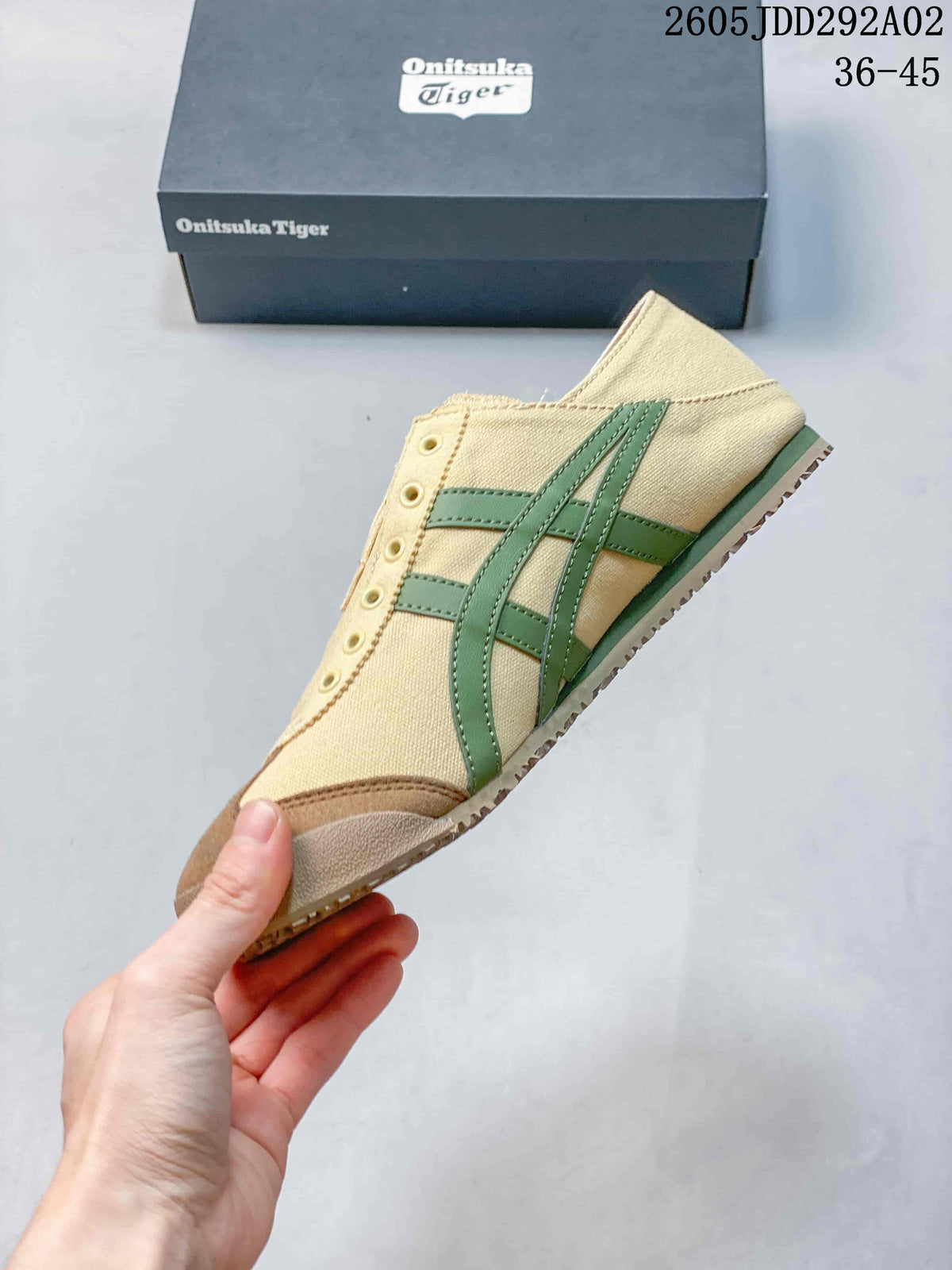 Side profile of the beige Onitsuka Tiger sneaker showing green signature stripes, brown toe overlays, and a low-profile outsole.