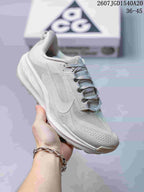 Angled side view of the light white and grey sneaker with its layered upper and textured outsole.