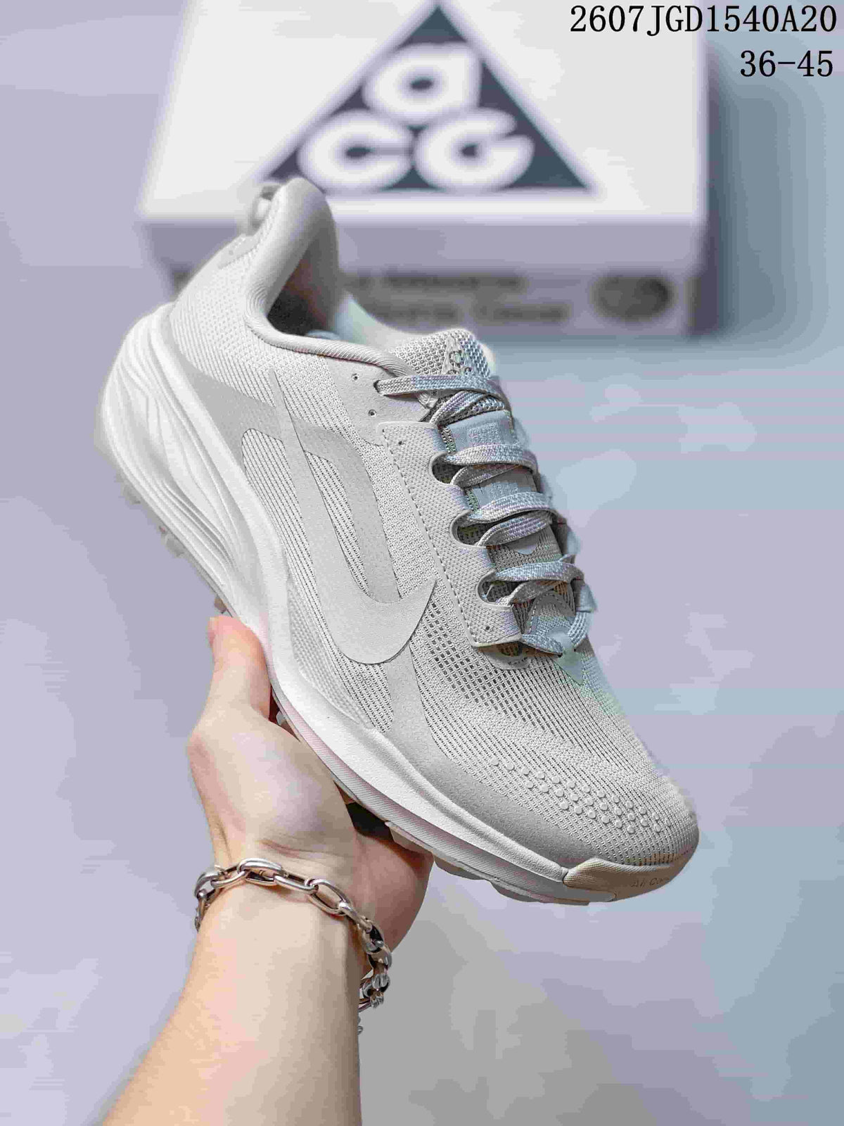 Angled side view of the light white and grey sneaker with its layered upper and textured outsole.