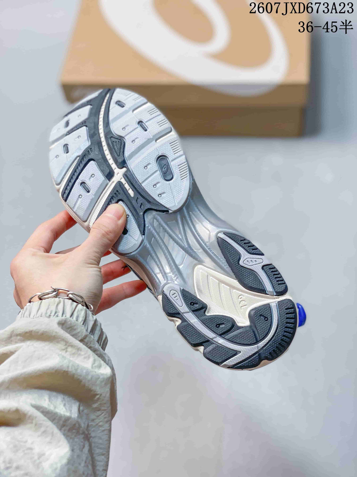 Underside view of the silver and blue sneaker showing the segmented black, gray, and white outsole pattern.