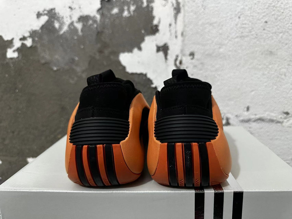 Rear view of black and orange basketball shoes showing ribbed heel details.