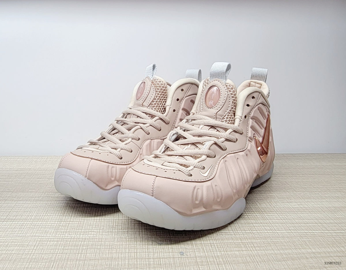 Pair of blush-pink Nike Air Foamposite Pro high-top sneakers viewed from the front
