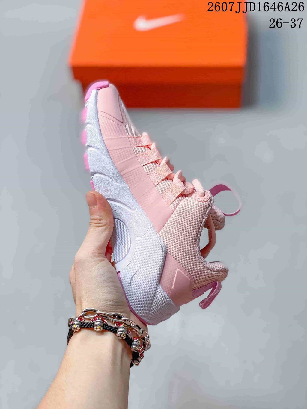 Side view of the pink and white training shoe showing the lace area, upper panels, heel pull tab, and white midsole section.