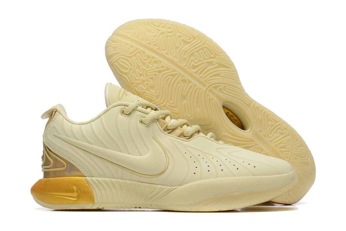 Pale yellow Nike basketball shoes with gold-toned heel accents.