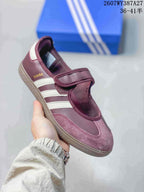 Close-up of a burgundy Samba Jane sneaker with white stripes, a hook-and-loop strap and textured outsole.