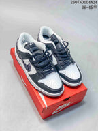 White and black Nike SB Dunk Low sneakers displayed on a red shoebox.