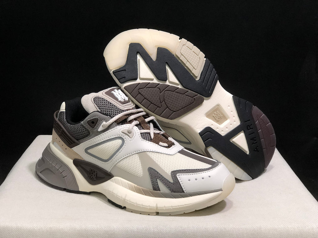 AMIRI MA Runner sneakers displayed with one shoe lifted to show the patterned outsole.