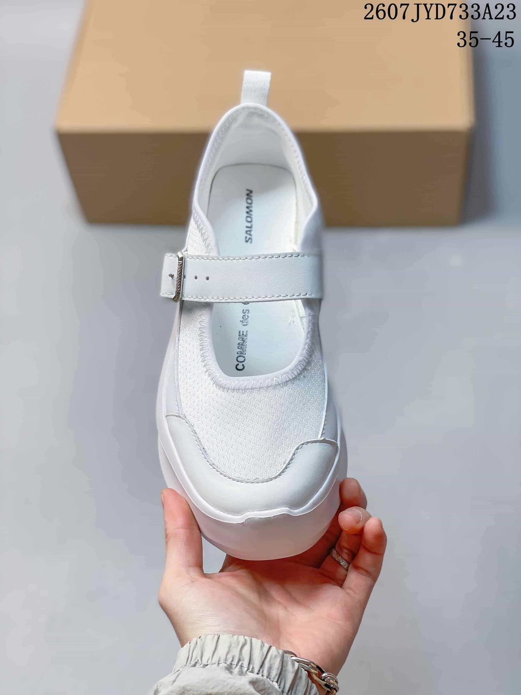 Top view of the white sneaker showing the adjustable buckle strap, rounded toe, and branded insole.