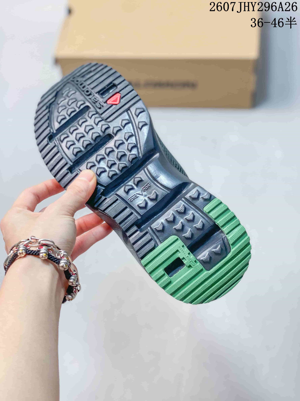 Close-up of the lugged outsole showing black tread with green sections and a red Salomon mark.