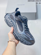 Angled side view of a black and dark gray Balenciaga Triple S.2 sneaker held against a light background.
