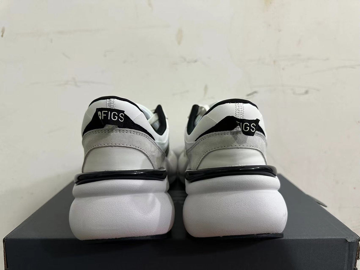 Rear view of white and light gray sneakers with black heel accents and a chunky white sole