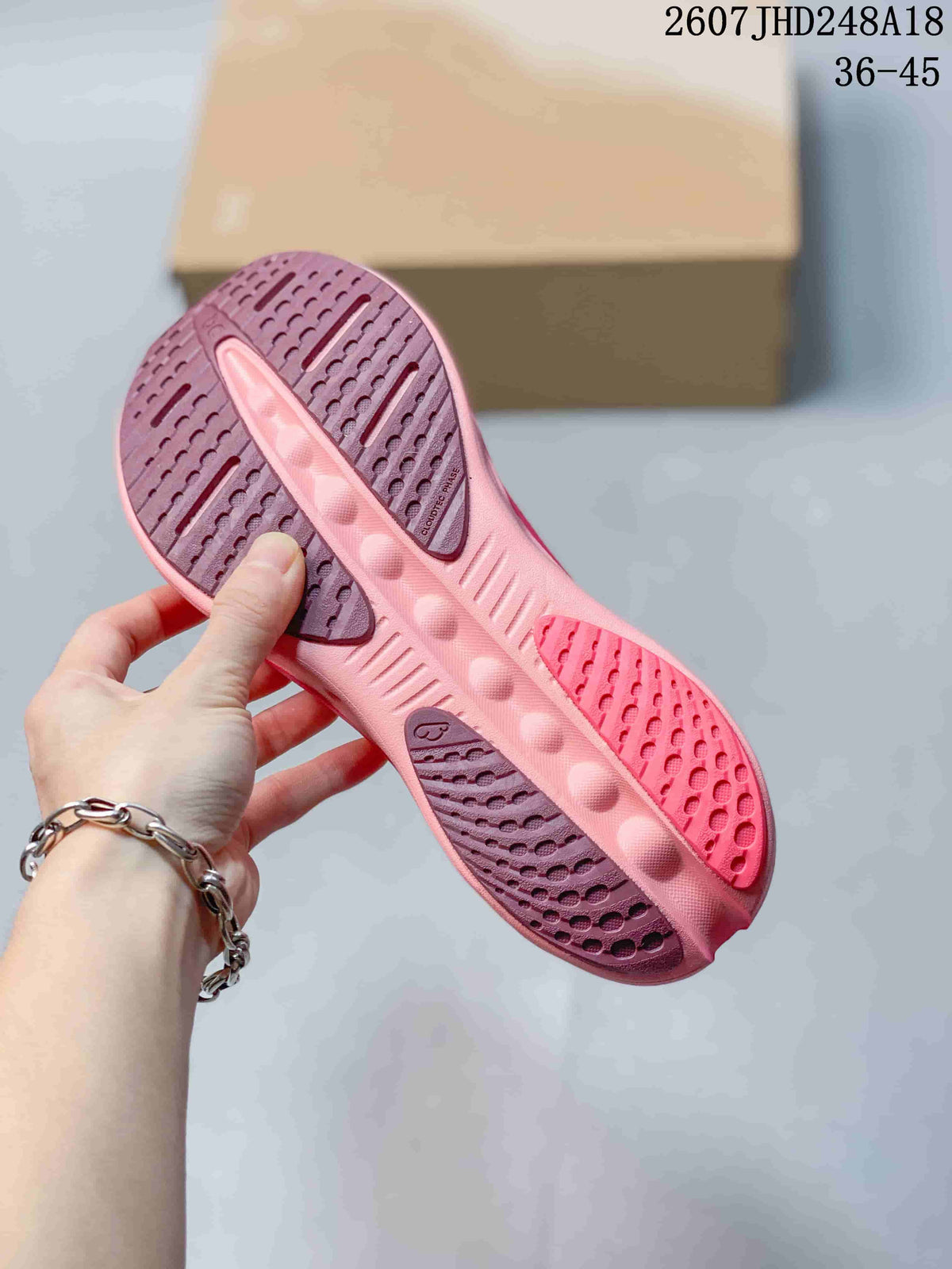 Underside view of a pink sneaker showing the patterned outsole and open-section construction.