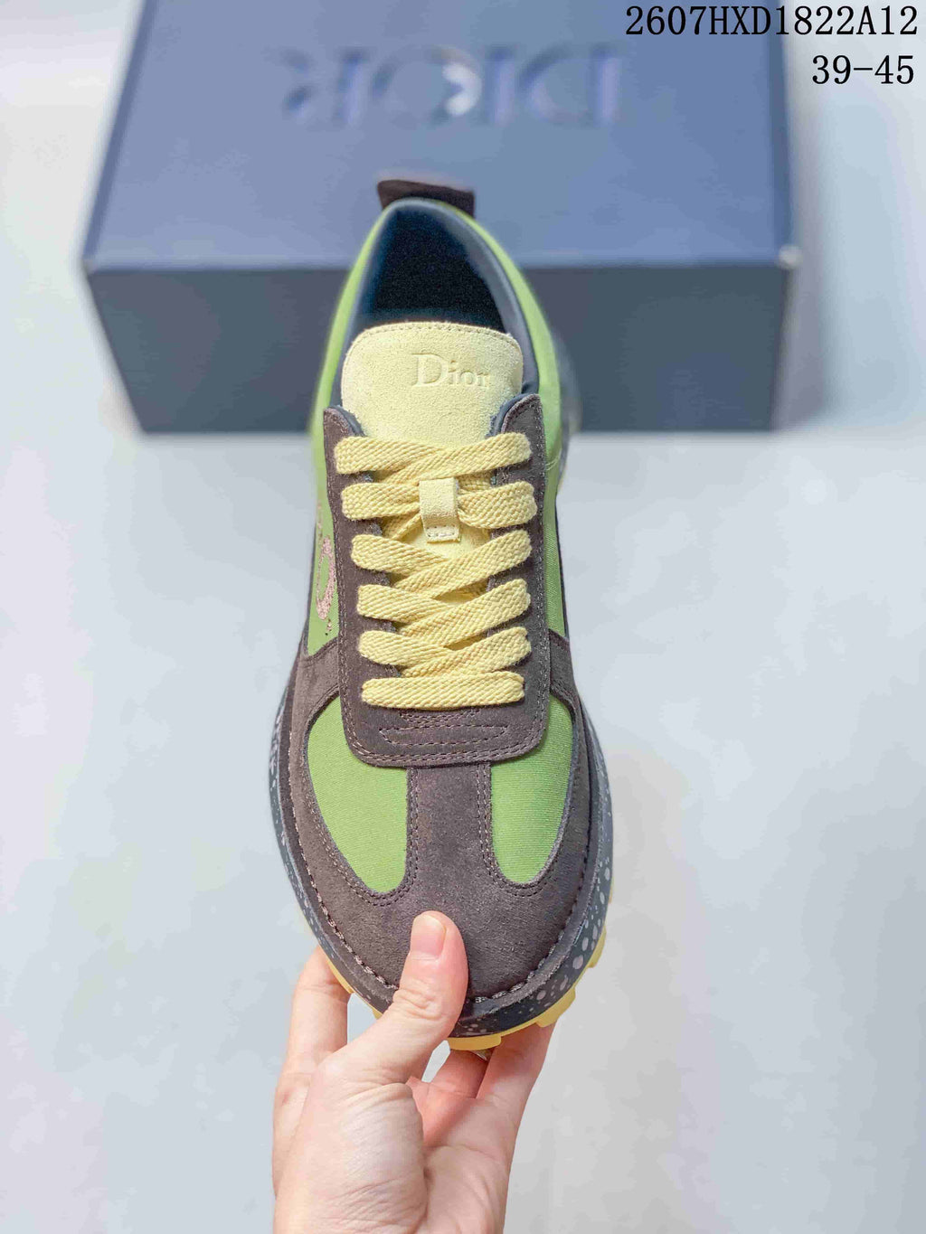 Top view of one sneaker showing the green and brown color-blocked upper, cream laces, and branded tongue.