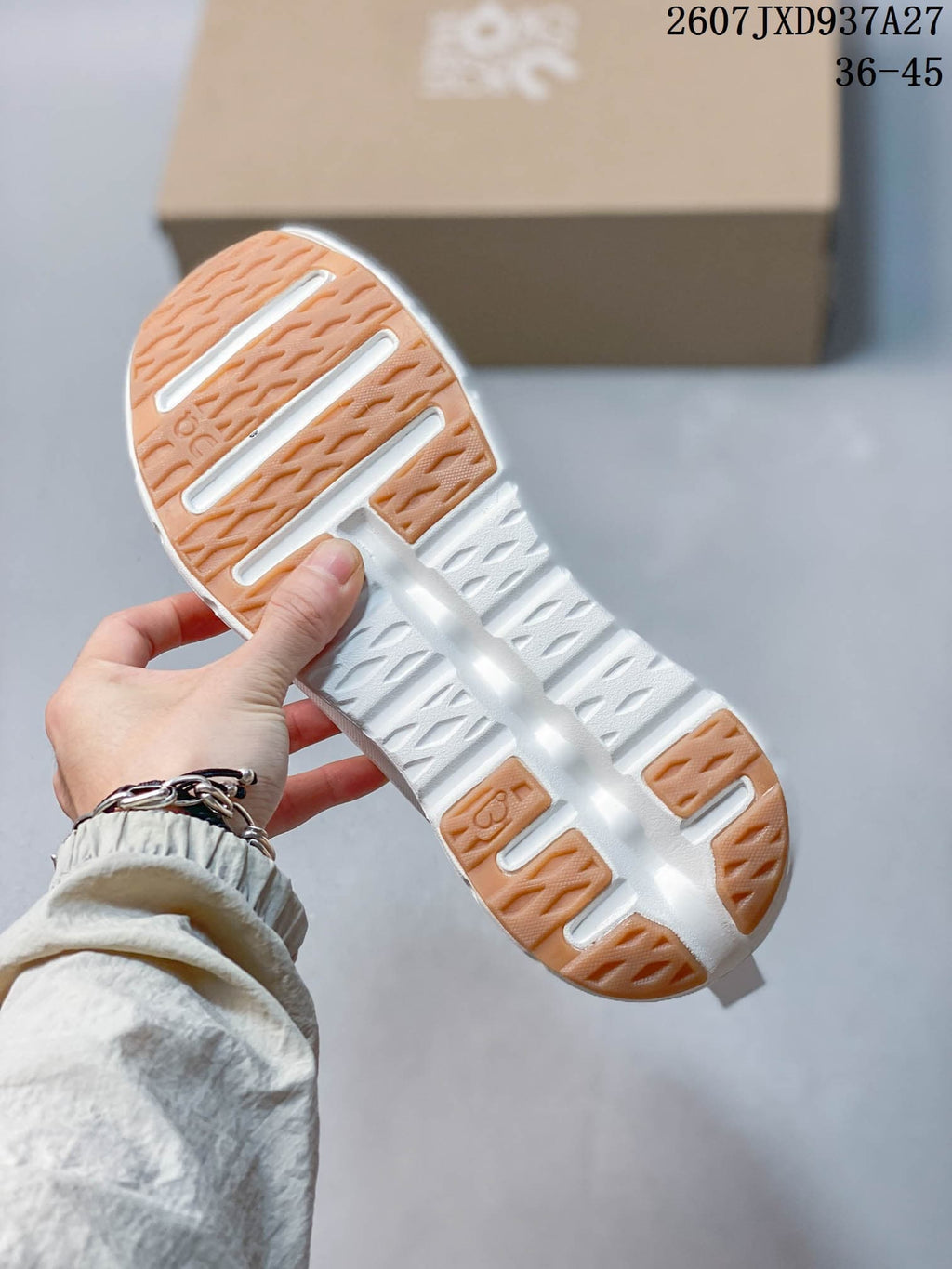 Close view of the white sneaker outsole showing segmented gum-colored traction sections and open cushioning channels.