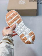 Close view of the white sneaker outsole showing segmented gum-colored traction sections and open cushioning channels.