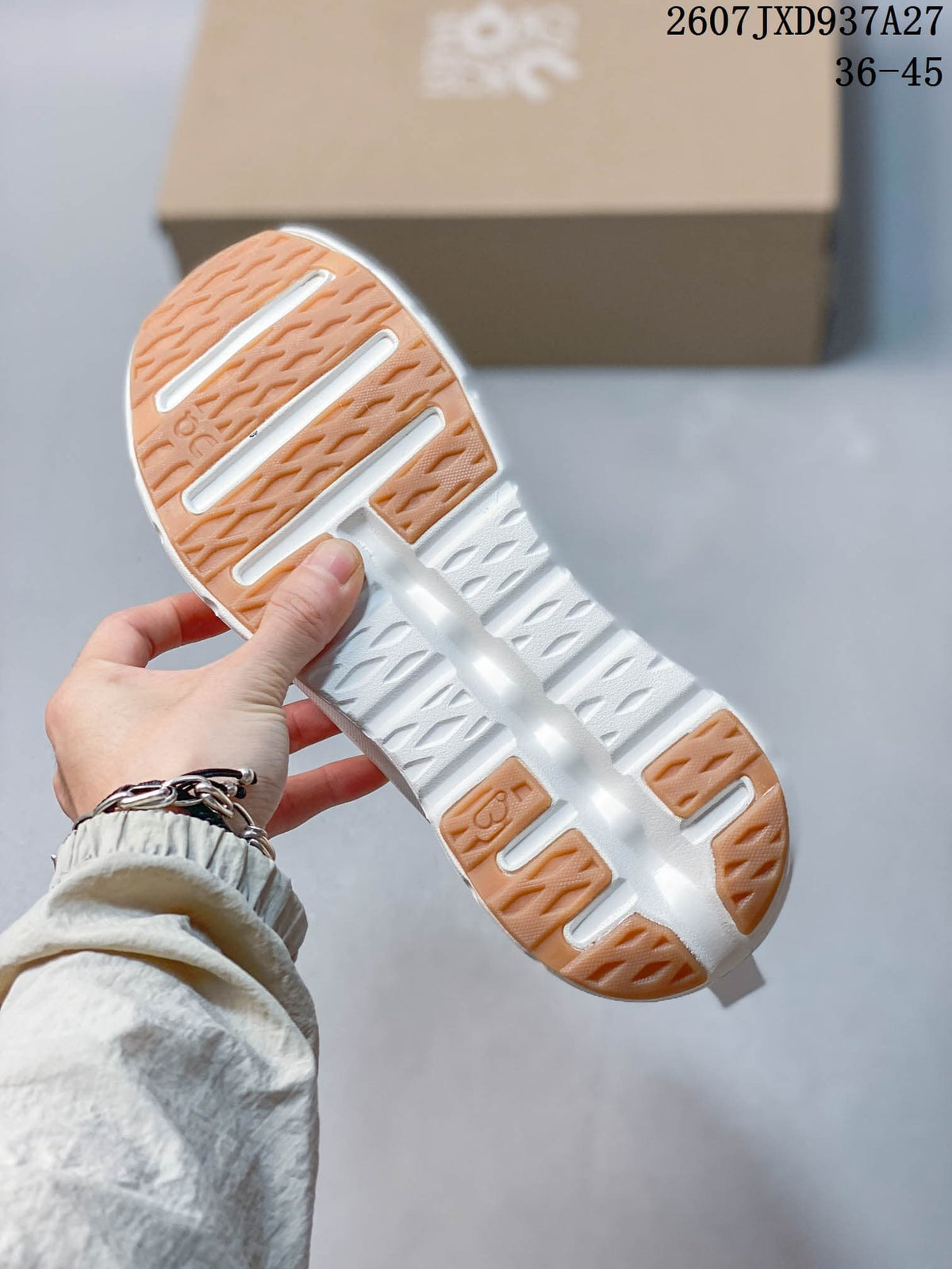 Close view of the white sneaker outsole showing segmented gum-colored traction sections and open cushioning channels.