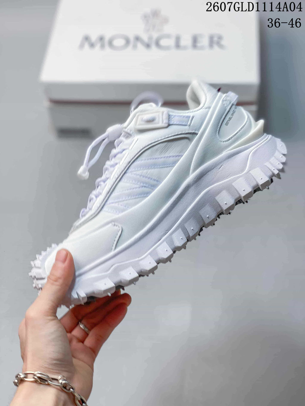 Side view of a white Moncler low-top sneaker showing its layered upper, padded collar and chunky sole.